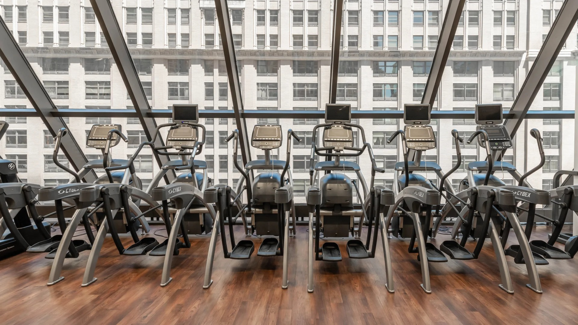 Cardio machines overlooking the city through large windows at Axis Apartments & Lofts in Chicago's fitness center