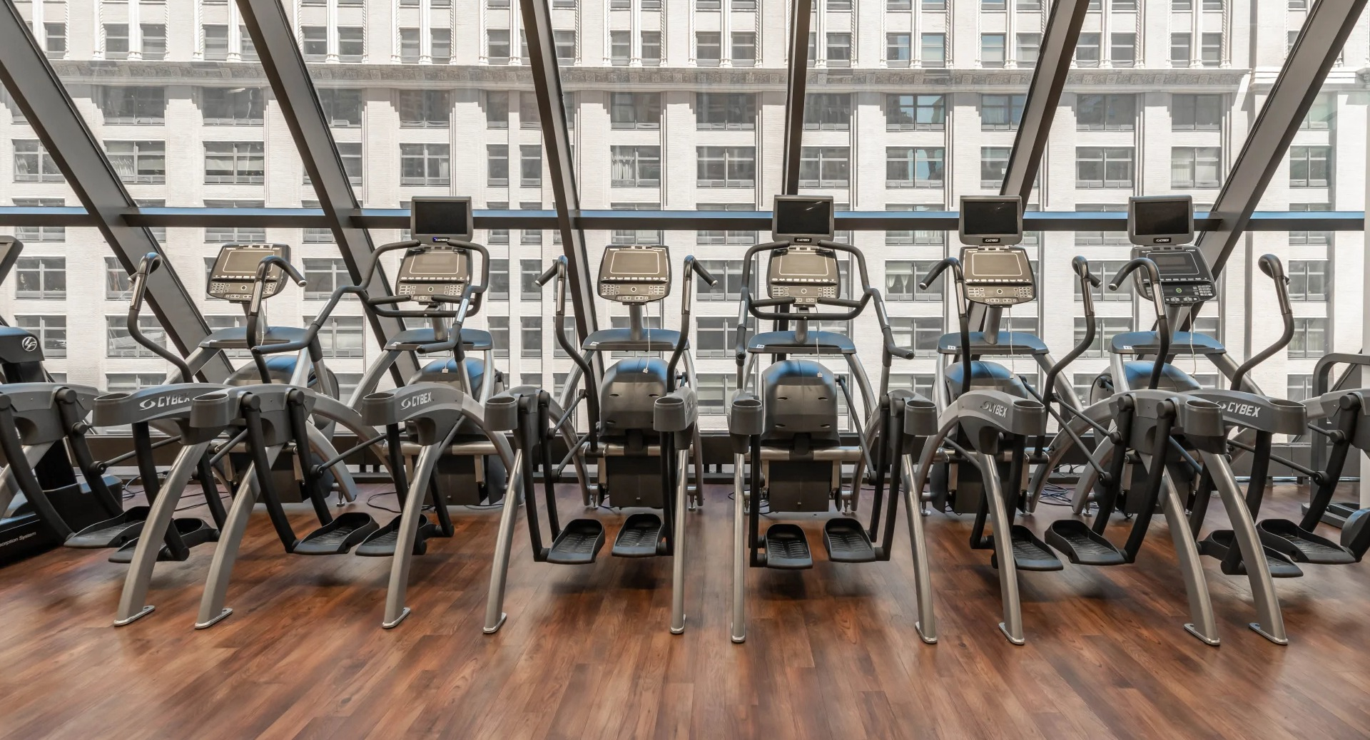Cardio machines overlooking the city through large windows at Axis Apartments & Lofts in Chicago's fitness center