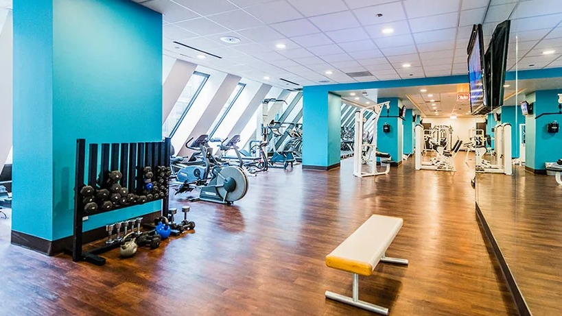 An expansive fitness center at Axis Apartments & Lofts in Chicago, with various equipment and bright blue accents