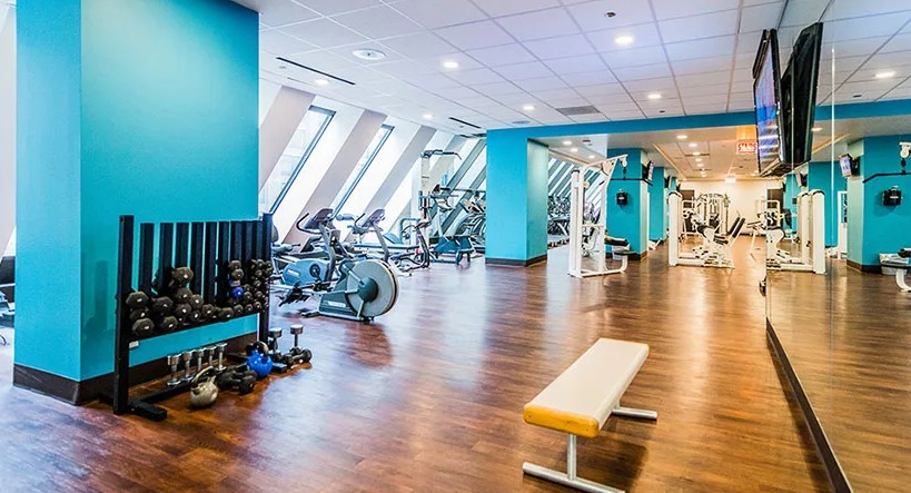 An expansive fitness center at Axis Apartments & Lofts in Chicago, with various equipment and bright blue accents