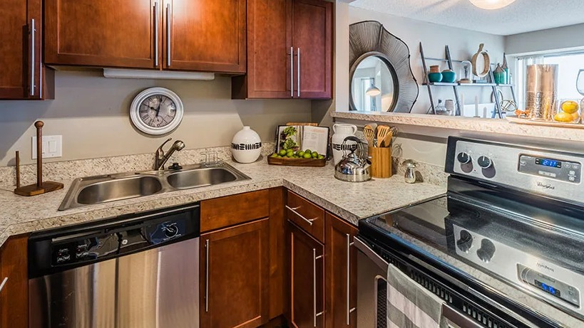 A functional galley kitchen with wood cabinetry and modern appliances at Axis Apartments & Lofts in Chicago