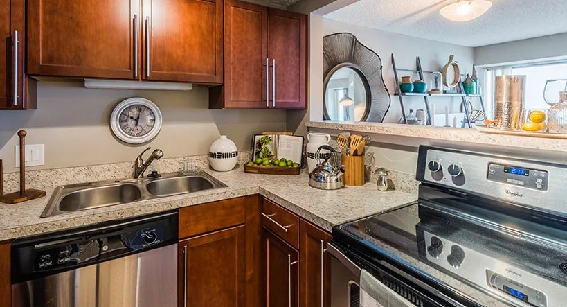 A functional galley kitchen with wood cabinetry and modern appliances at Axis Apartments & Lofts in Chicago