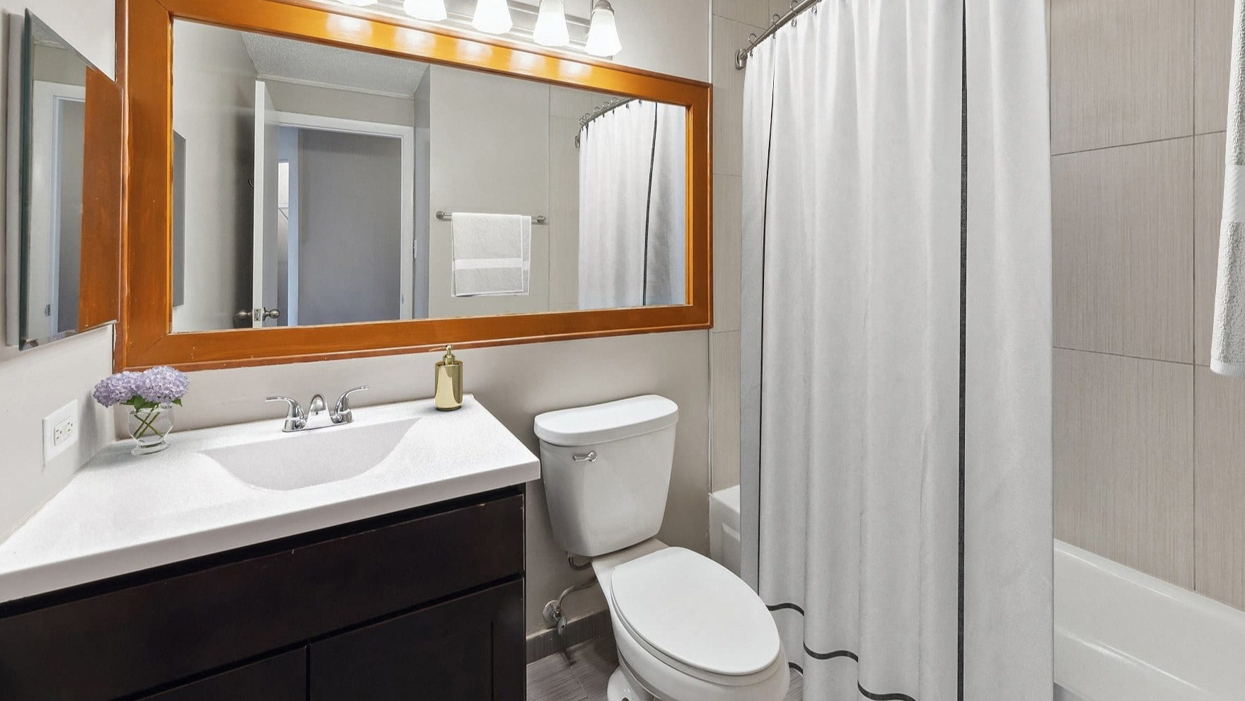 Modern bathroom with a shower-tub combo and sleek vanity at Axis Apartments & Lofts in Chicago