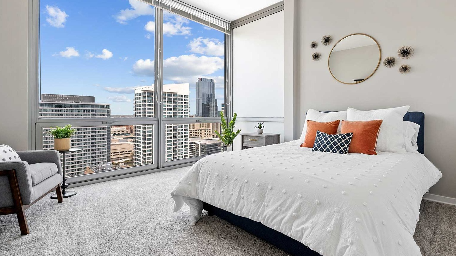 Inviting bedroom with plush carpeting, a comfortable bed, stylish decor, and large windows offering city views at Burnham Pointe in Chicago