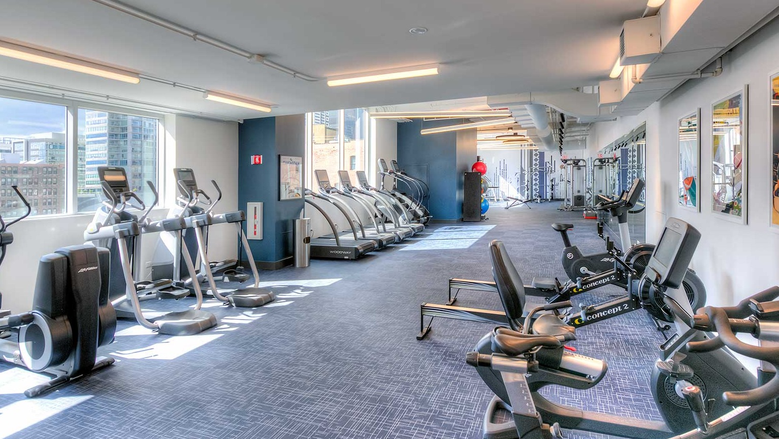 Modern fitness center featuring a wide array of cardio machines including treadmills and ellipticals, at Burnham Pointe apartments in Chicago