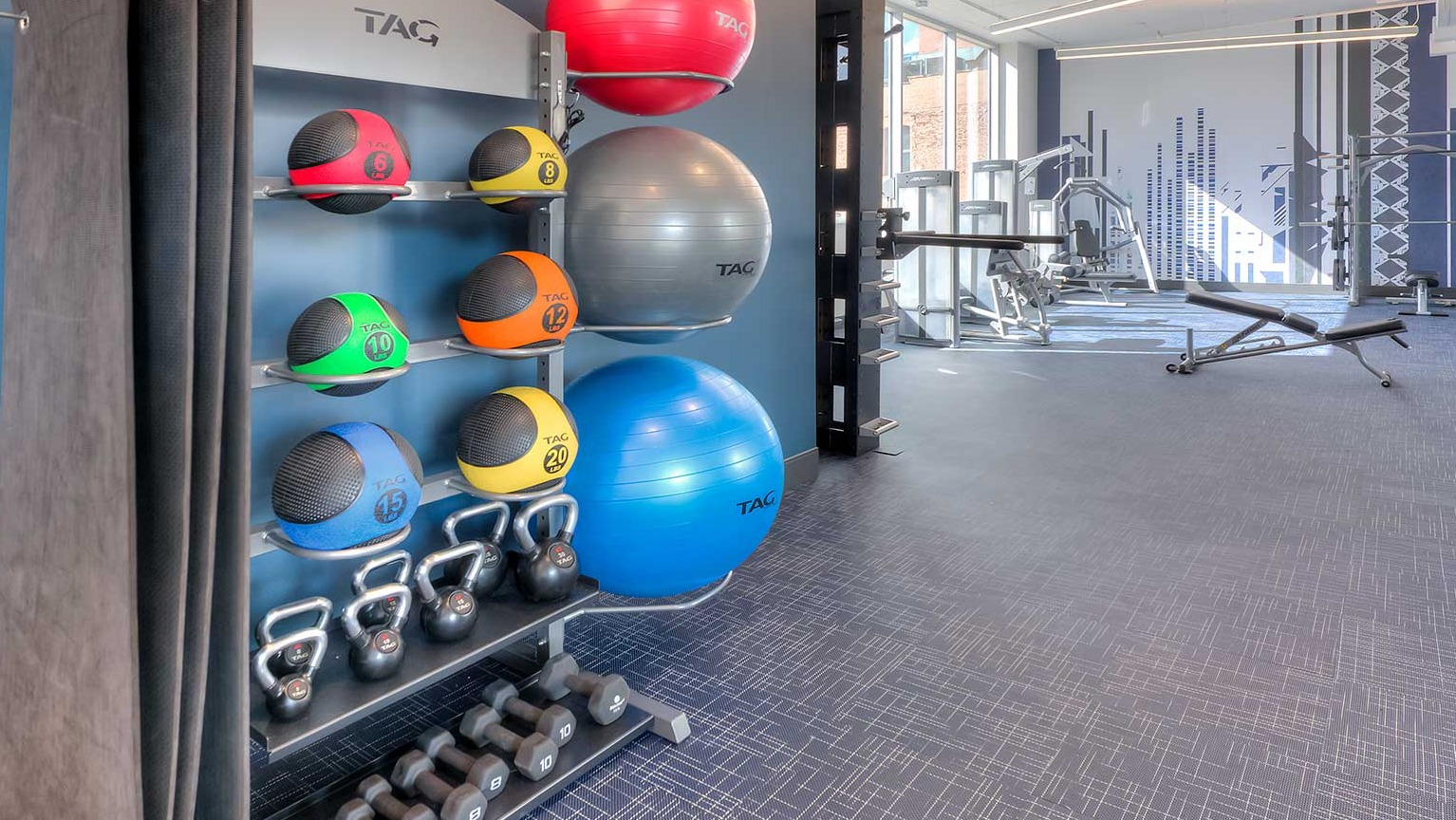 Dedicated area in the gym with a rack of medicine balls, kettlebells, and dumbbells, for strength training at Burnham Pointe in Chicago
