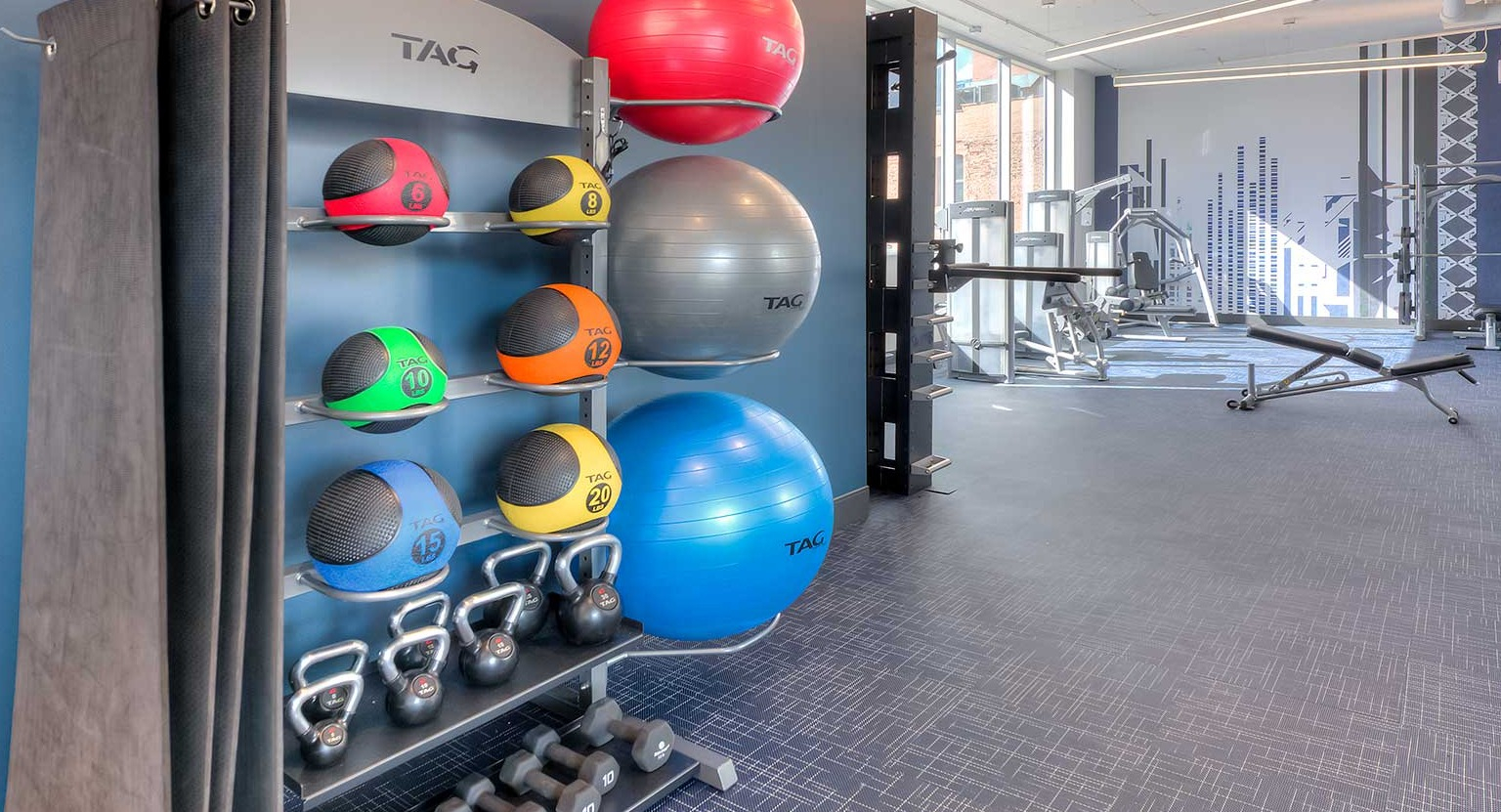 Dedicated area in the gym with a rack of medicine balls, kettlebells, and dumbbells, for strength training at Burnham Pointe in Chicago