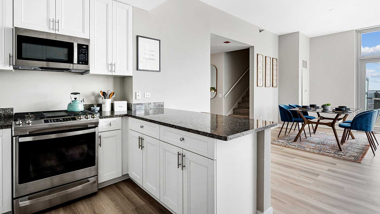 Modern kitchen with white cabinets, stainless steel appliances, and an open-concept flow to the dining area at Burnham Pointe in Chicago