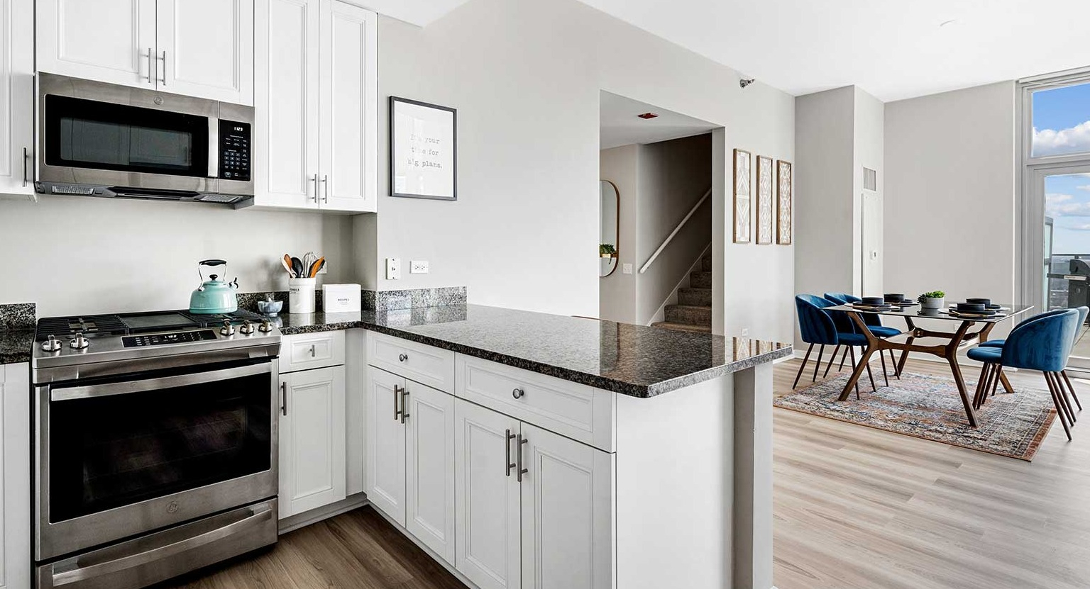 Modern kitchen with white cabinets, stainless steel appliances, and an open-concept flow to the dining area at Burnham Pointe in Chicago