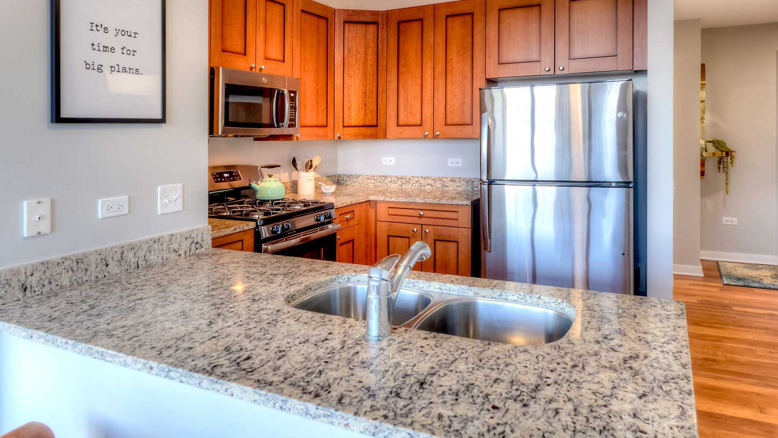 Well-appointed kitchen featuring granite countertops, stainless steel appliances, and wood cabinetry, at Burnham Pointe apartments in Chicago