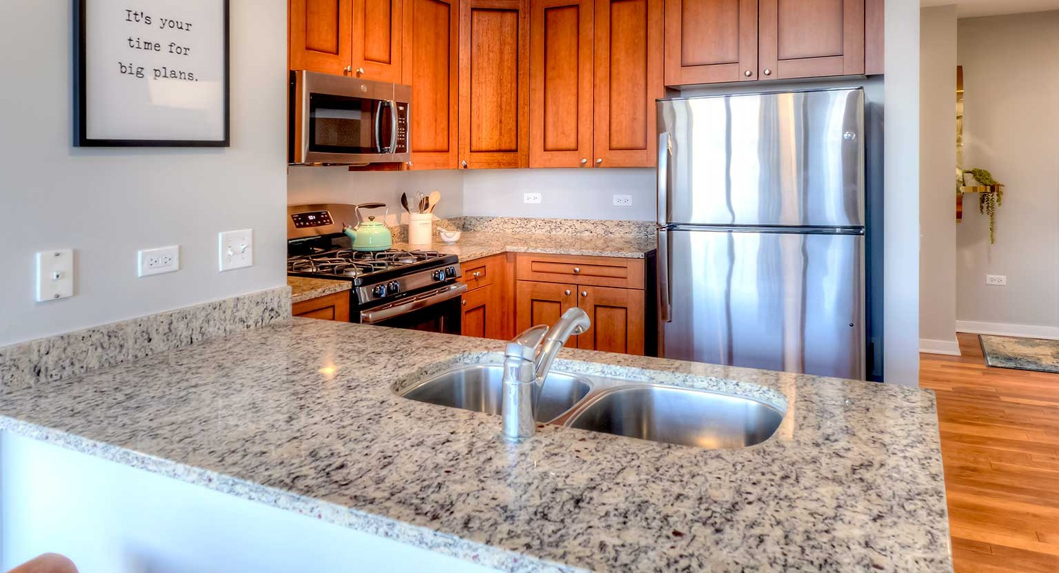 Well-appointed kitchen featuring granite countertops, stainless steel appliances, and wood cabinetry, at Burnham Pointe apartments in Chicago