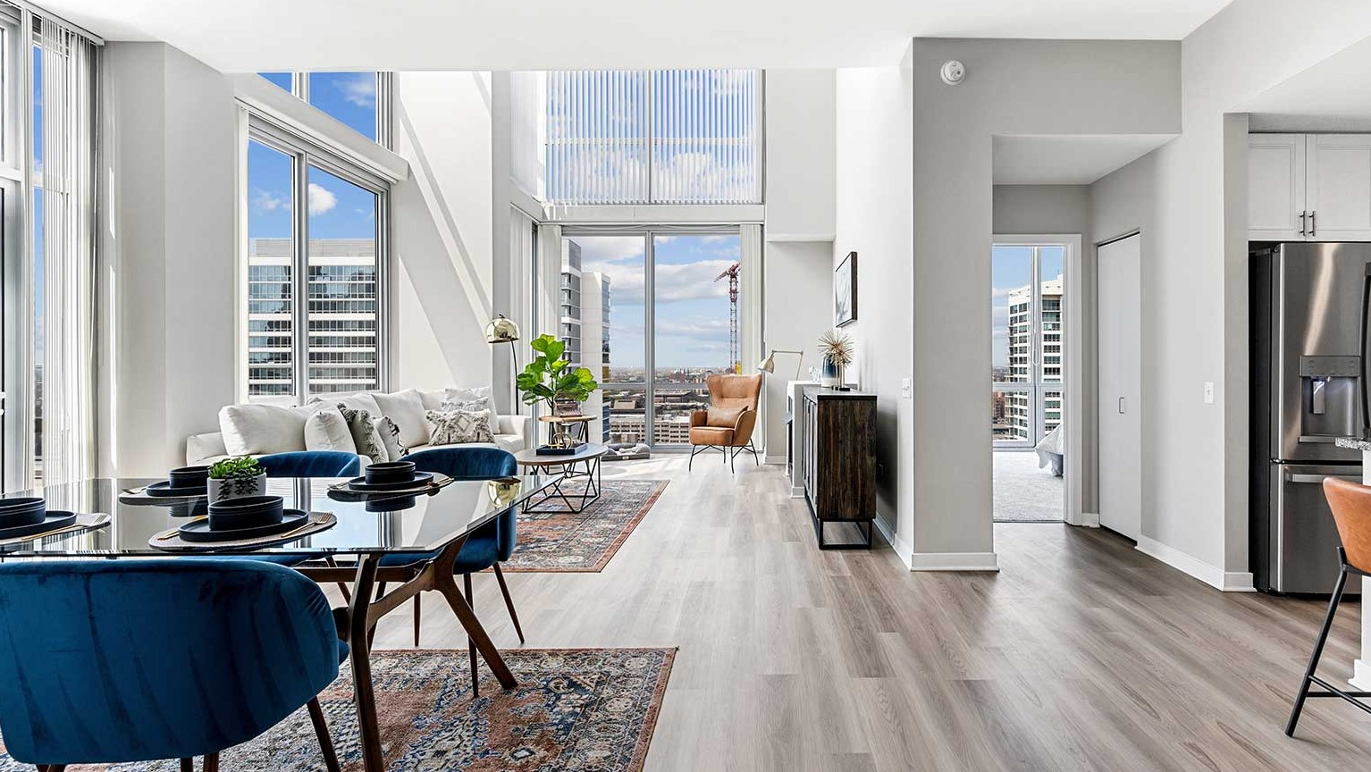 Expansive living and dining area with modern furniture, hardwood floors, and stunning two-story windows at Burnham Pointe in Chicago