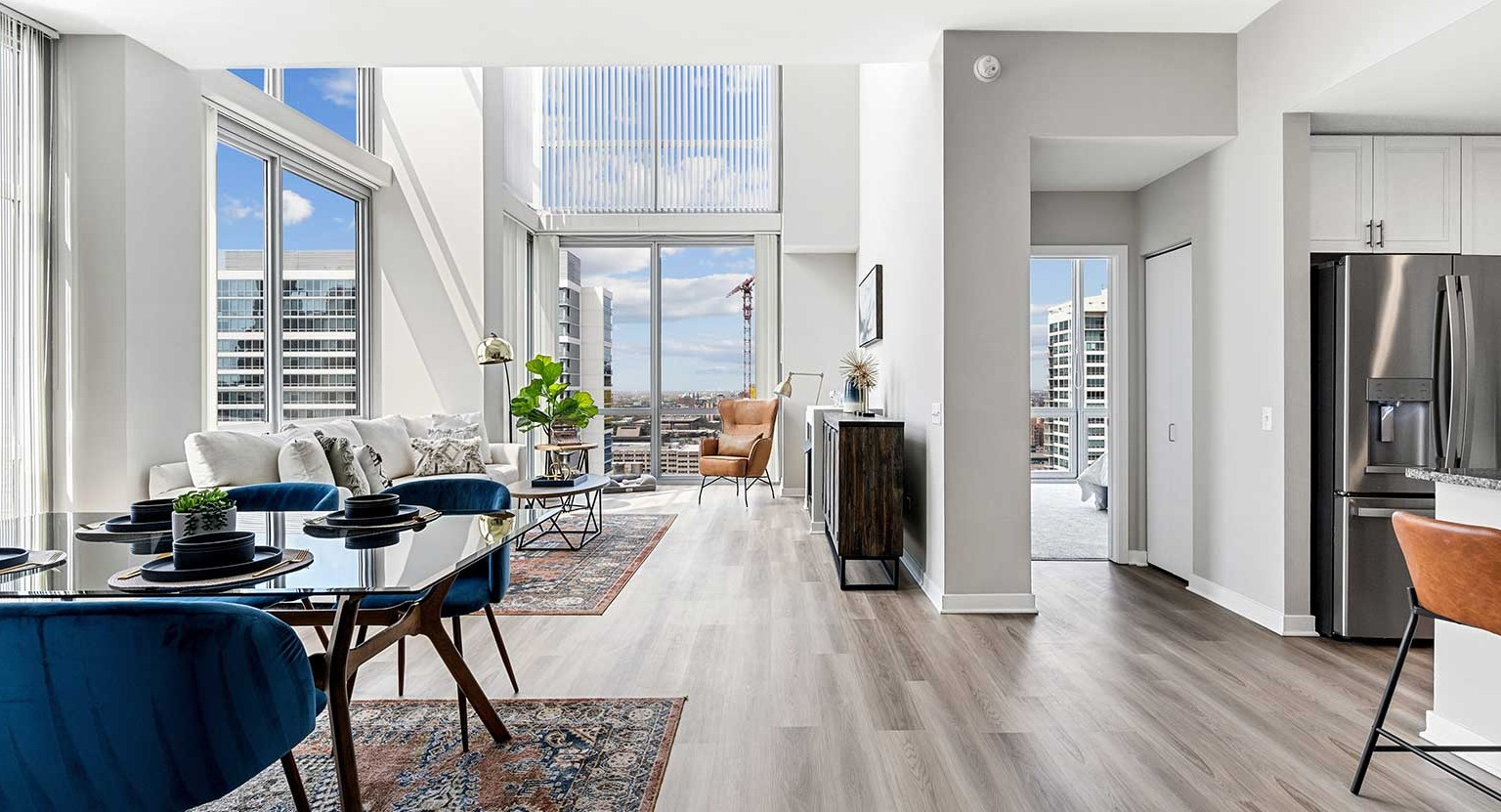 Expansive living and dining area with modern furniture, hardwood floors, and stunning two-story windows at Burnham Pointe in Chicago