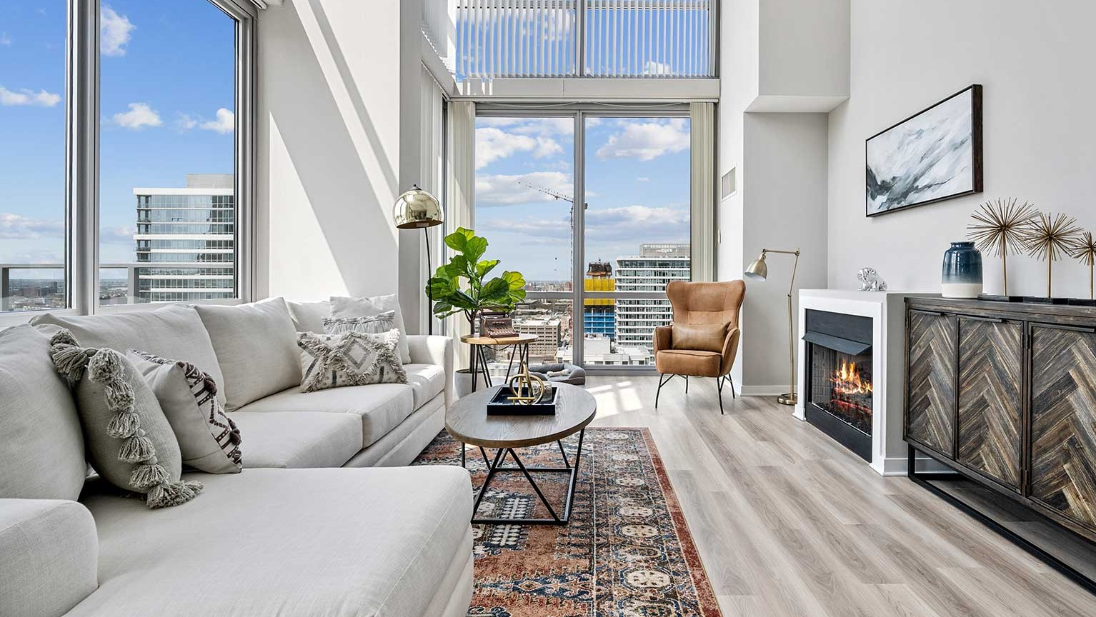 Stylish living room featuring a cozy fireplace, comfortable seating, and panoramic city views from tall windows at Burnham Pointe in Chicago