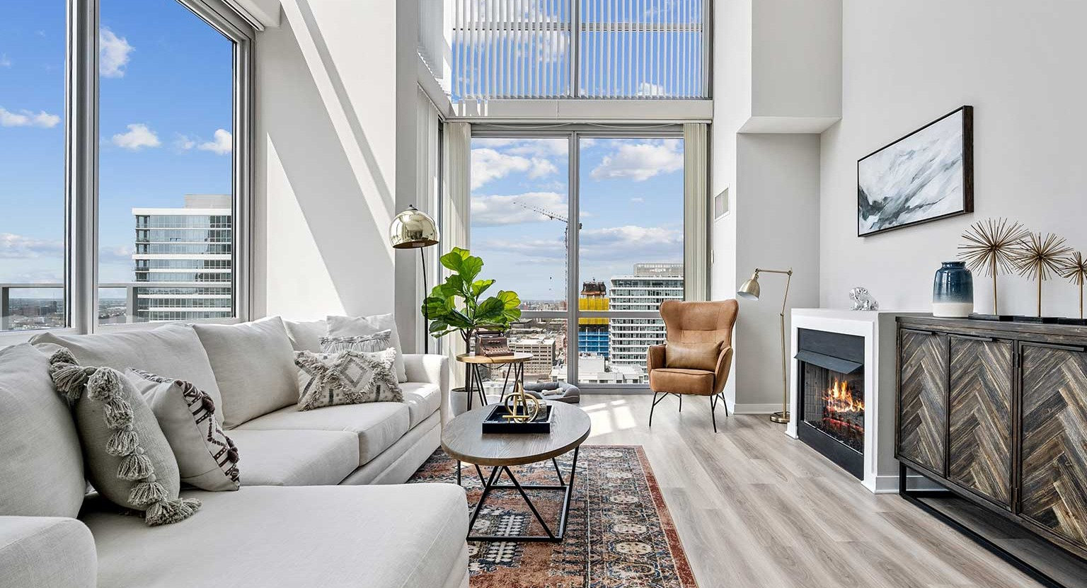 Stylish living room featuring a cozy fireplace, comfortable seating, and panoramic city views from tall windows at Burnham Pointe in Chicago