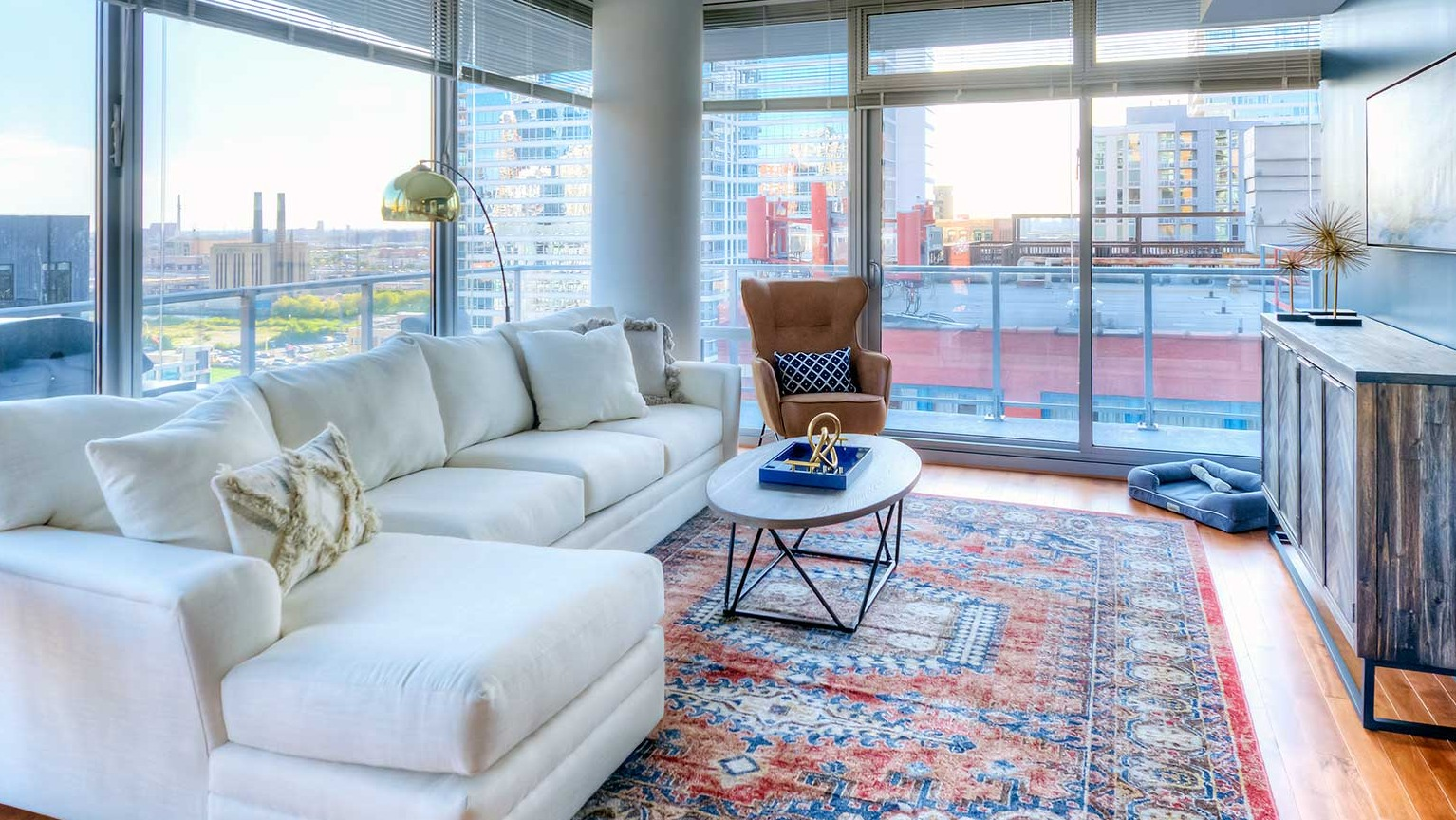 Cozy living room with a large white sofa, a comfortable armchair, and direct access to a private balcony at Burnham Pointe in Chicago