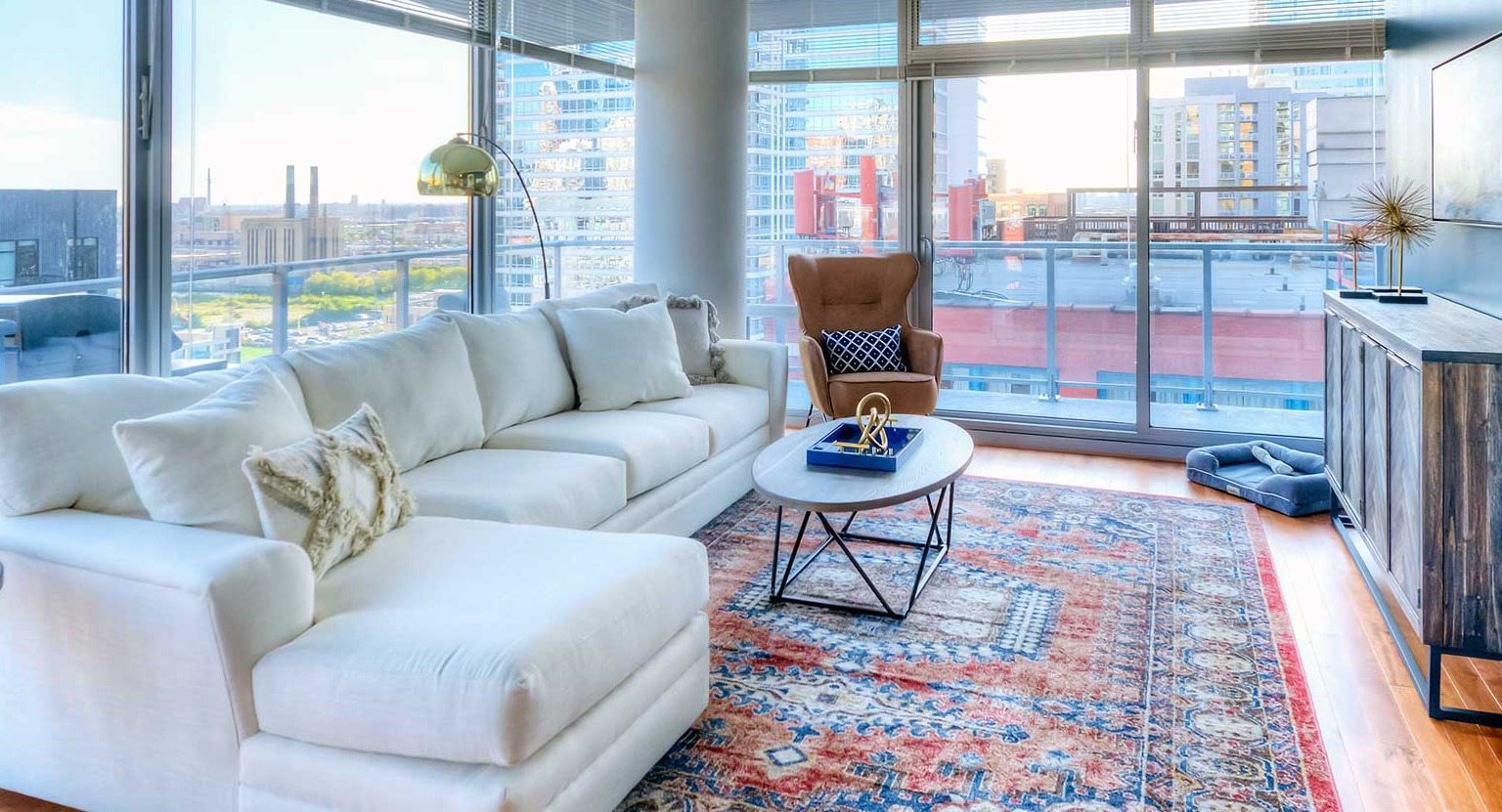 Cozy living room with a large white sofa, a comfortable armchair, and direct access to a private balcony at Burnham Pointe in Chicago