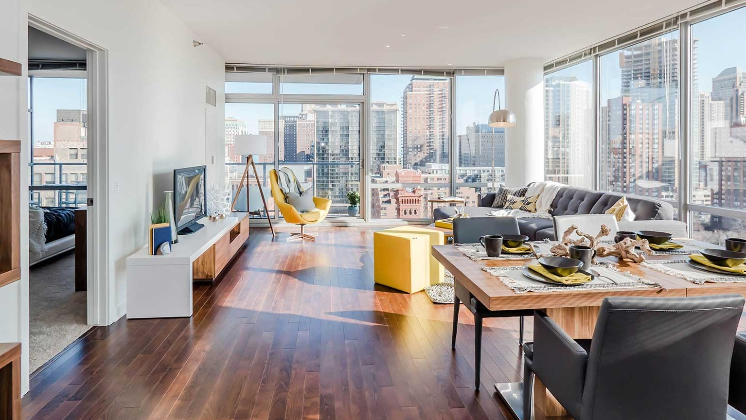 Bright open-concept dining and living area with hardwood floors, a modern dining table, and city views at Burnham Pointe apartments in Chicago