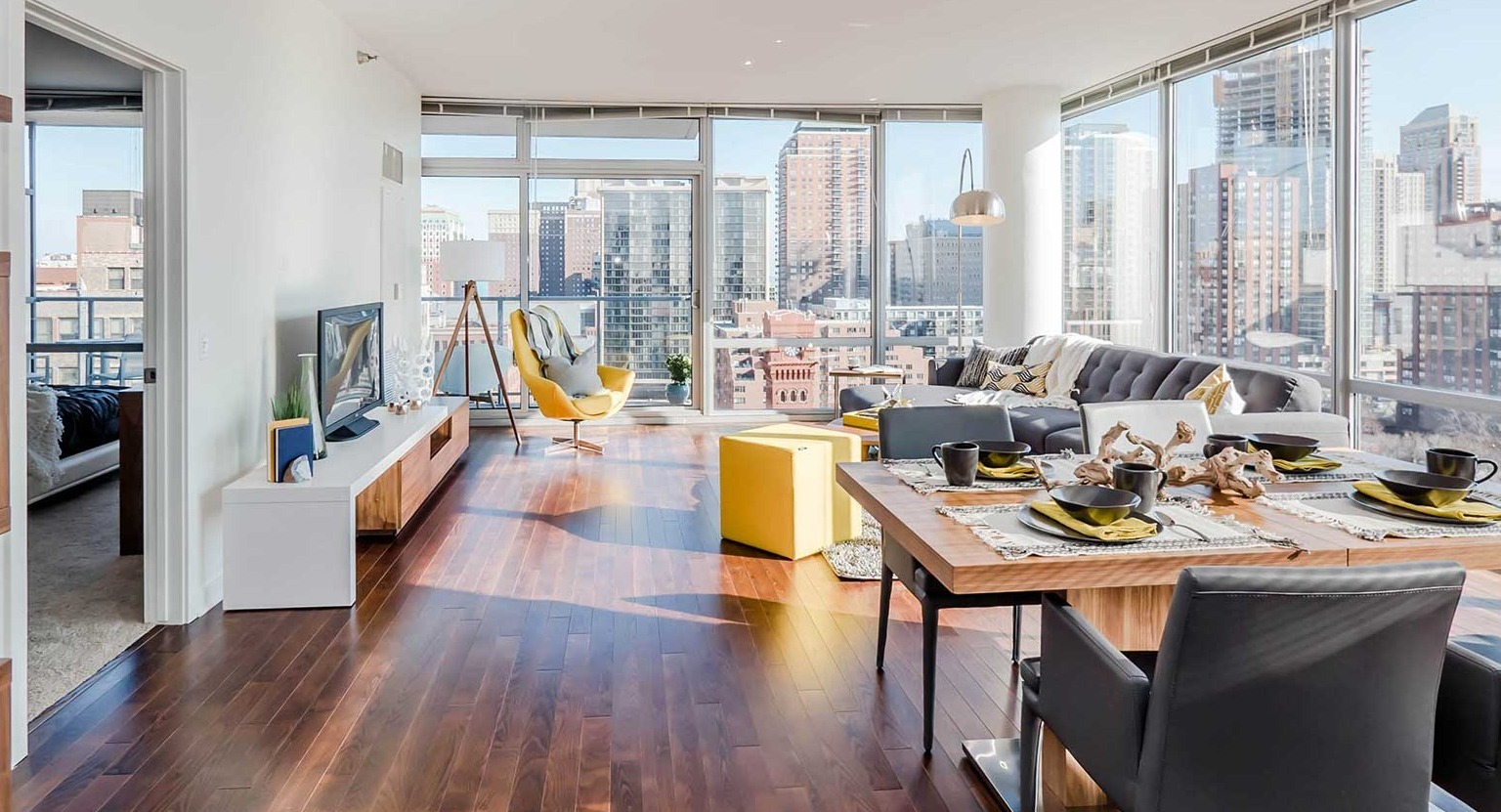 Bright open-concept dining and living area with hardwood floors, a modern dining table, and city views at Burnham Pointe apartments in Chicago