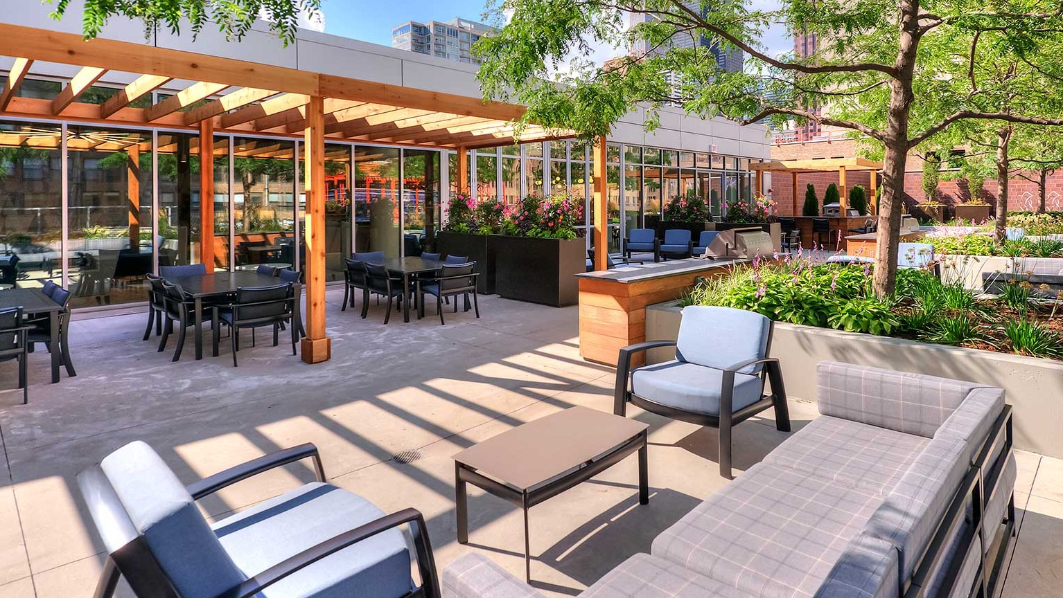 Beautiful outdoor courtyard and patio area with shaded seating, dining tables, and lush landscaping, ideal for relaxation at Burnham Pointe in Chicago