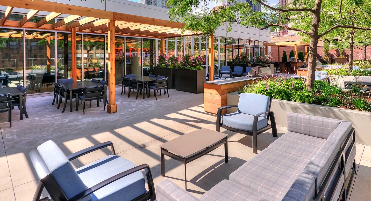 Beautiful outdoor courtyard and patio area with shaded seating, dining tables, and lush landscaping, ideal for relaxation at Burnham Pointe in Chicago