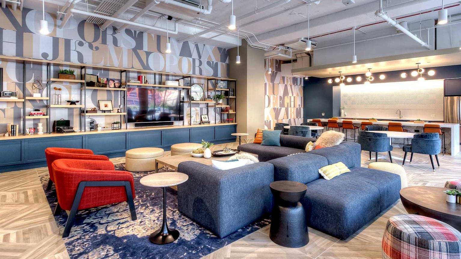 Vibrant resident lounge with comfortable seating, decorative shelving, and a modern kitchen area, at Burnham Pointe apartments in Chicago