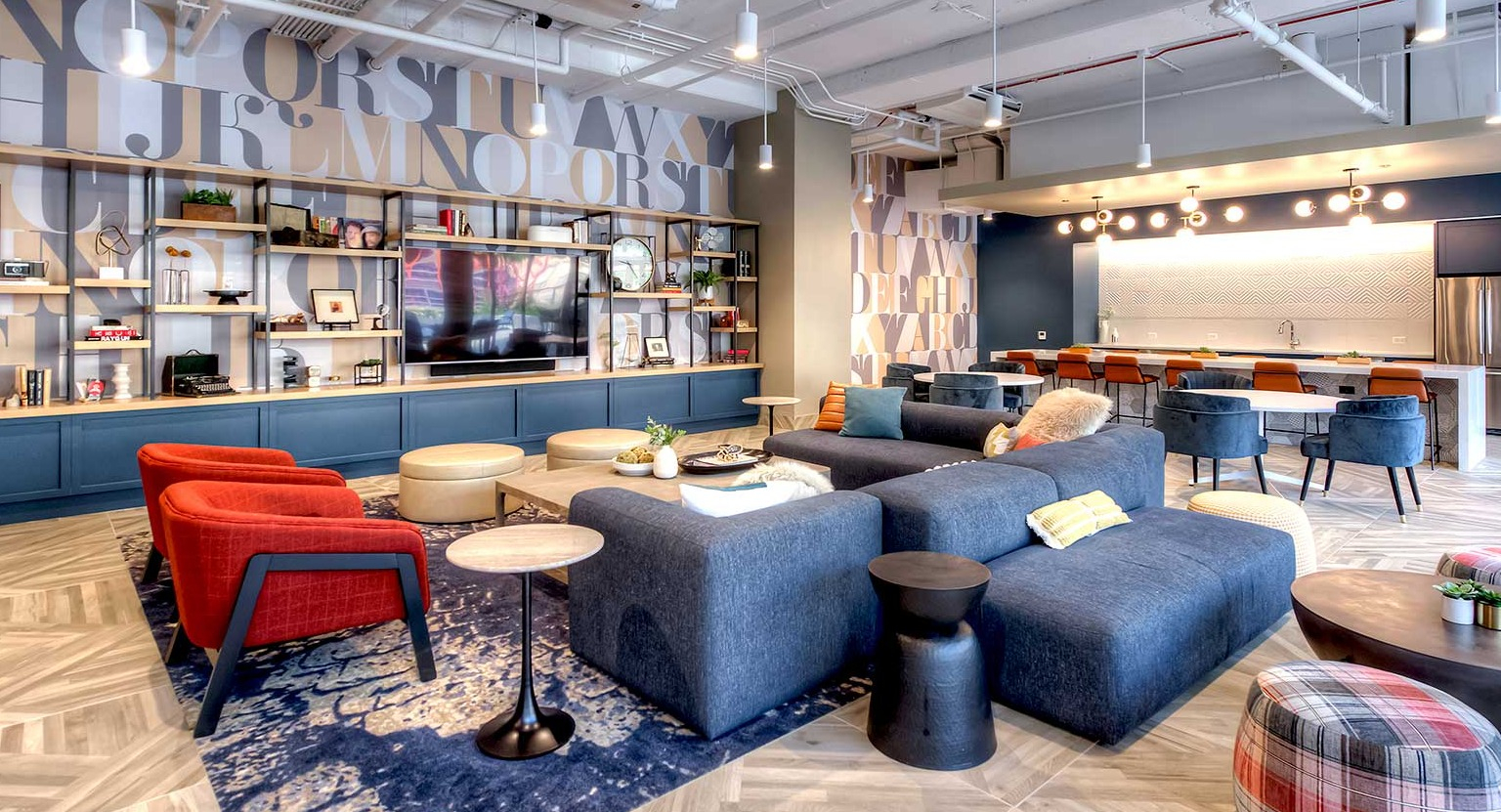 Vibrant resident lounge with comfortable seating, decorative shelving, and a modern kitchen area, at Burnham Pointe apartments in Chicago