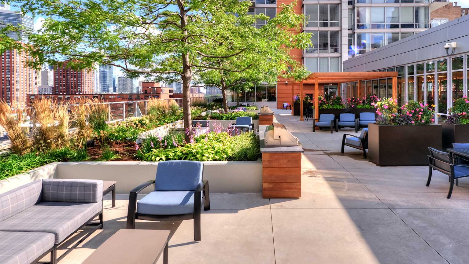 Expansive rooftop deck with comfortable lounge seating, dining areas, and lush greenery, offering city views at Burnham Pointe in Chicago