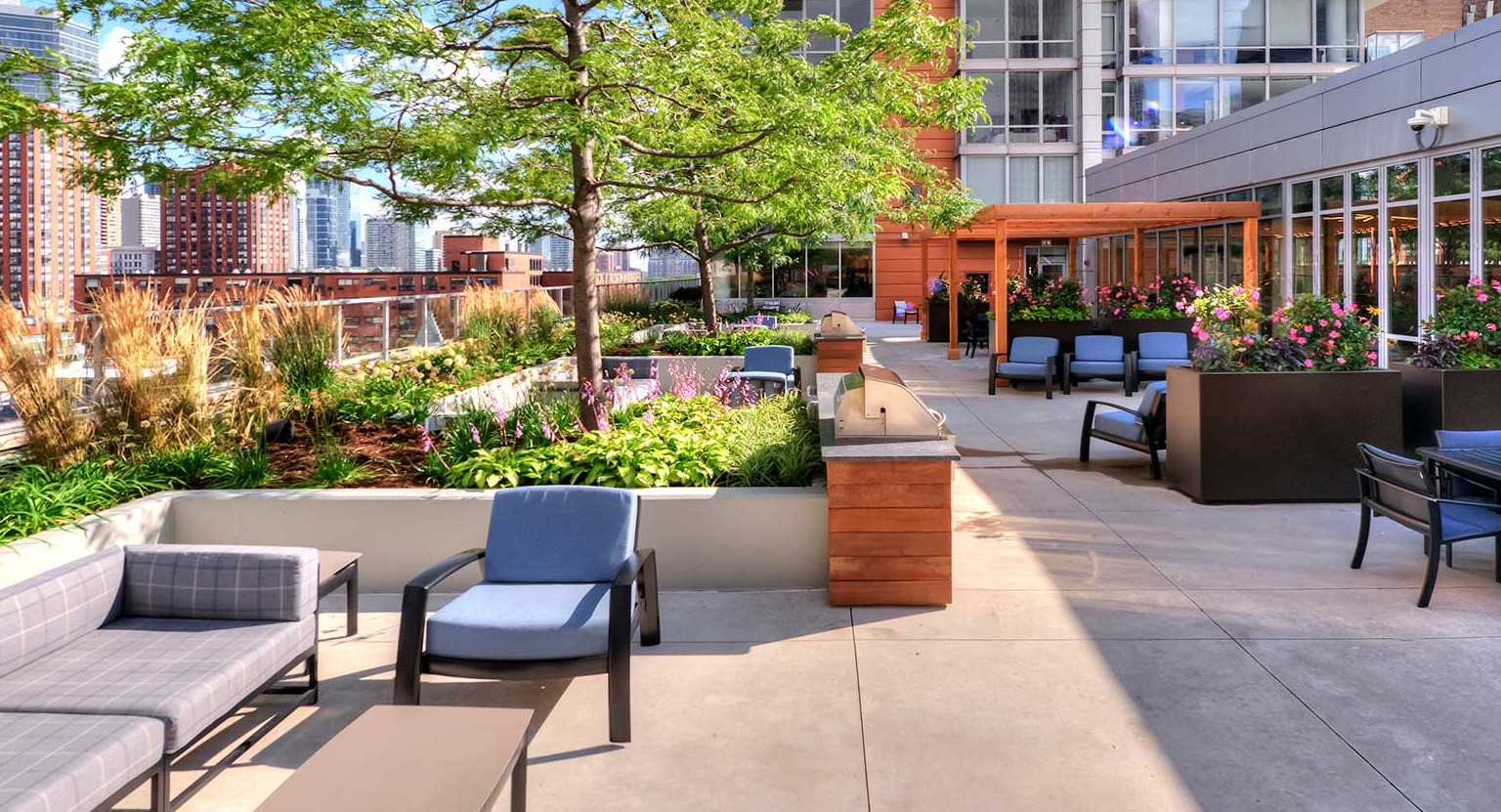Expansive rooftop deck with comfortable lounge seating, dining areas, and lush greenery, offering city views at Burnham Pointe in Chicago