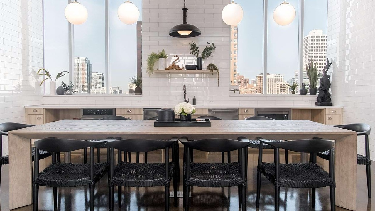 Spacious community dining room at The Bush Temple in Chicago, featuring a large communal table, stylish lighting, and city views