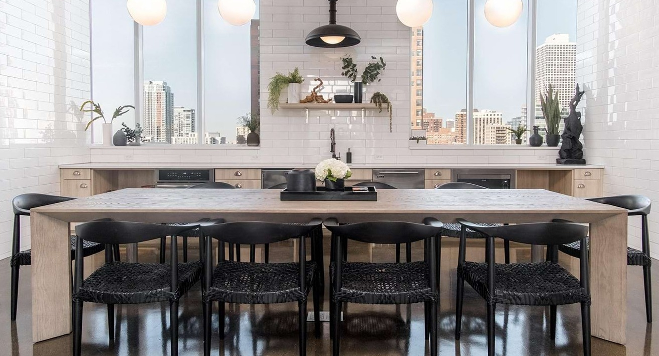 Spacious community dining room at The Bush Temple in Chicago, featuring a large communal table, stylish lighting, and city views