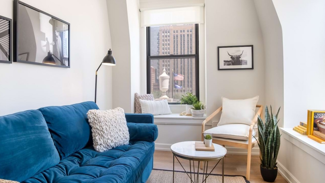 Cozy living room at The Bush Temple in Chicago, featuring a comfortable blue sofa, window seat, and city views