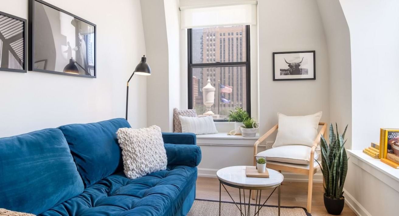 Cozy living room at The Bush Temple in Chicago, featuring a comfortable blue sofa, window seat, and city views