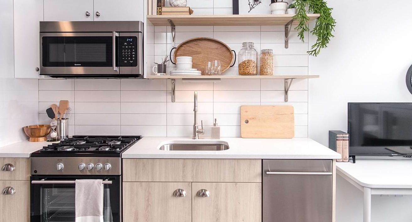 Modern apartment kitchen at The Bush Temple in Chicago, featuring white subway tiles, stainless steel appliances, and an integrated desk area