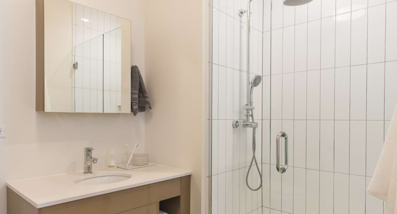 Modern apartment bathroom at The Bush Temple in Chicago, featuring a sleek vanity, mirror, and a spacious walk-in shower
