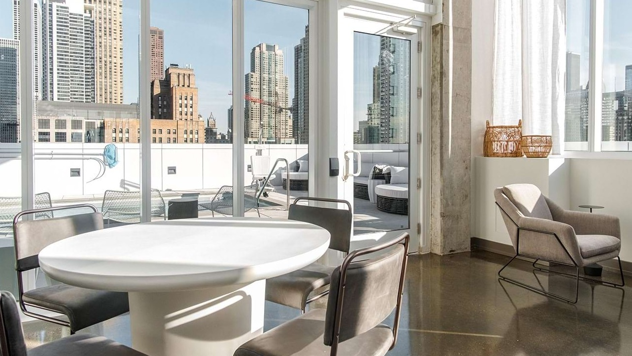 Bright resident lounge at The Bush Temple in Chicago, featuring a round table, comfortable seating, and access to an outdoor terrace