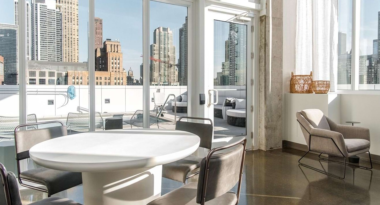 Bright resident lounge at The Bush Temple in Chicago, featuring a round table, comfortable seating, and access to an outdoor terrace