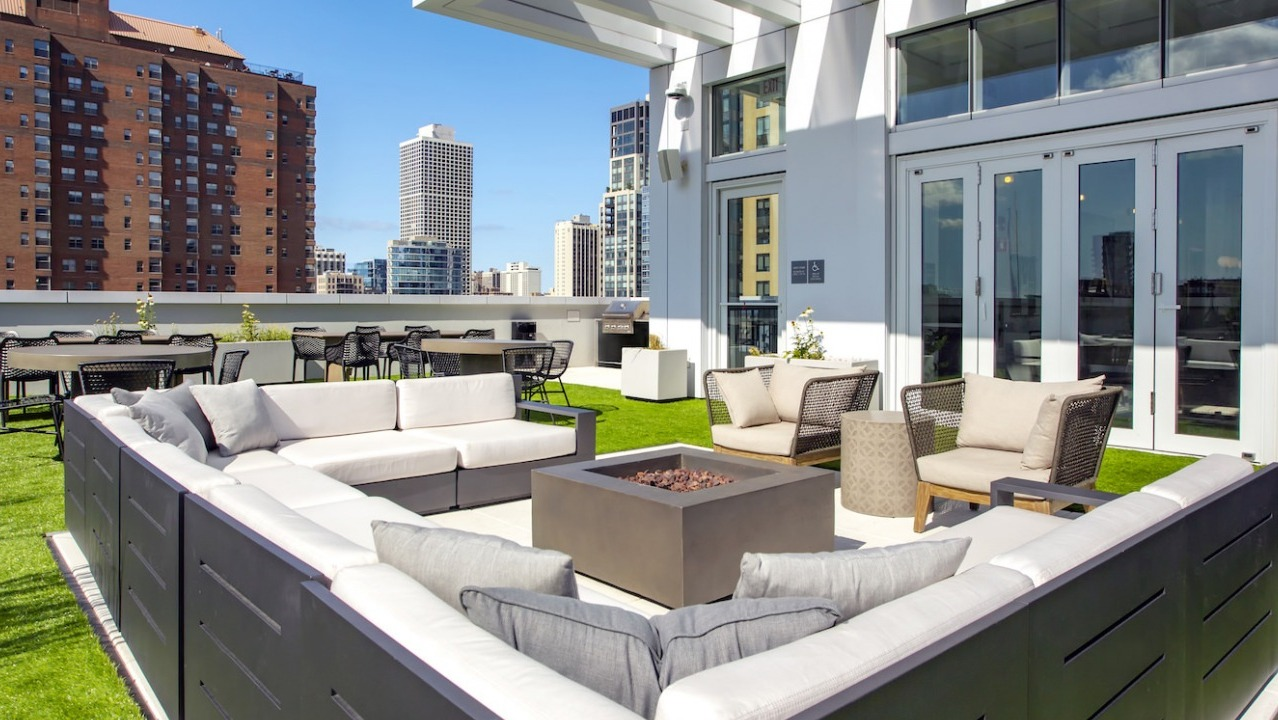Luxurious rooftop patio at The Bush Temple in Chicago, featuring comfortable lounge seating around a fire pit and city views