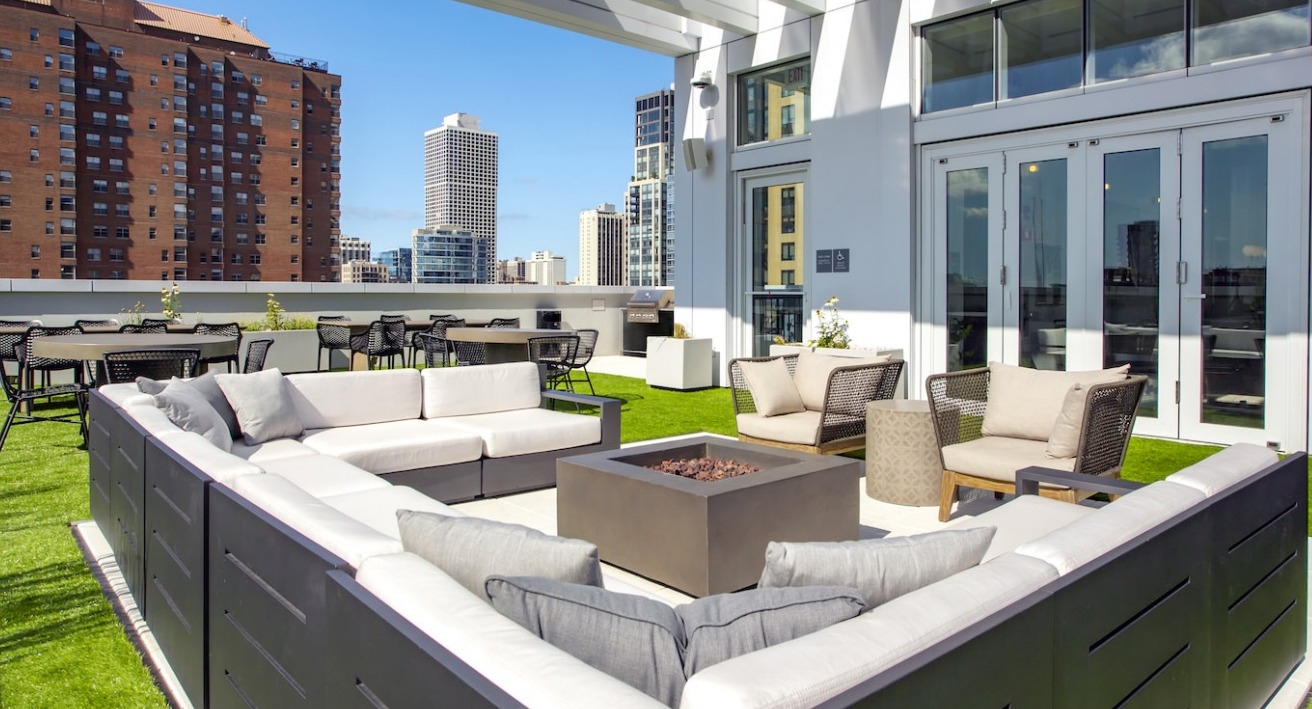 Luxurious rooftop patio at The Bush Temple in Chicago, featuring comfortable lounge seating around a fire pit and city views