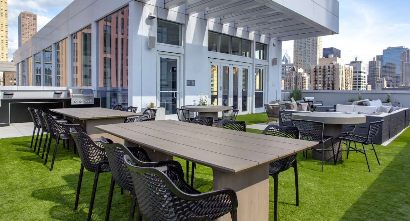 Expansive rooftop grilling and lounge area at The Bush Temple in Chicago, featuring outdoor dining tables and comfortable seating