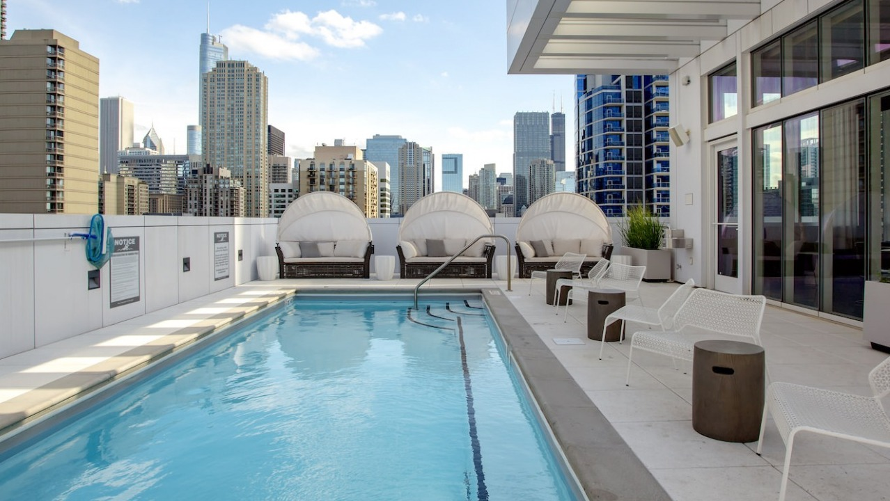 Luxurious rooftop swimming pool at The Bush Temple in Chicago, featuring comfortable cabanas and stunning city views