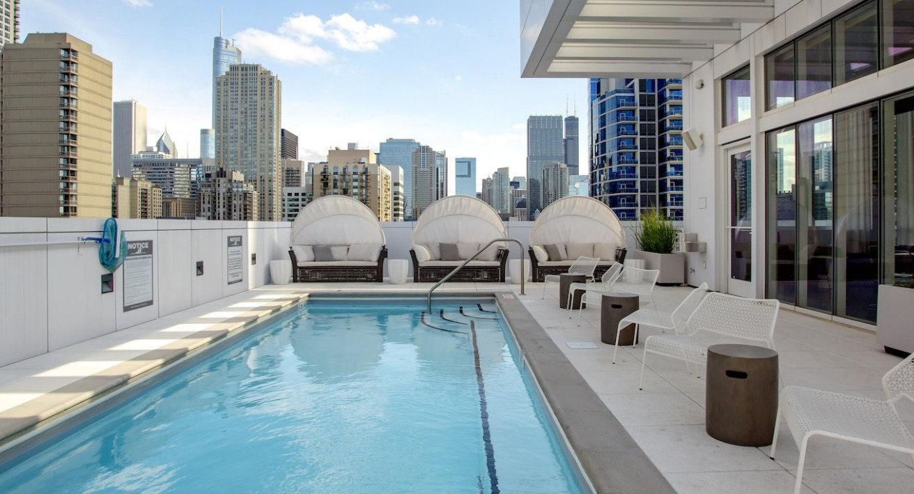 Luxurious rooftop swimming pool at The Bush Temple in Chicago, featuring comfortable cabanas and stunning city views