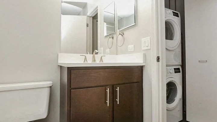 Bathroom with modern vanity, toilet, and a convenient in-unit stacked washer and dryer at Carriage House Lofts in Chicago