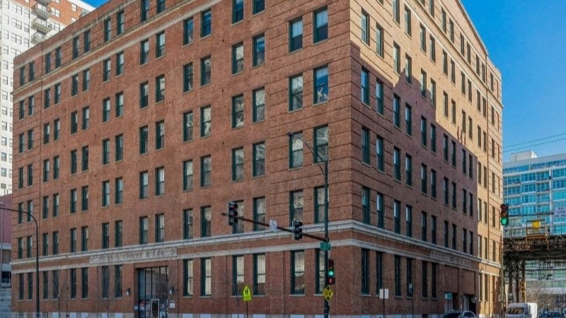 Exterior of Carriage House Lofts building, a brick facade with multiple windows on a sunny day in Chicago