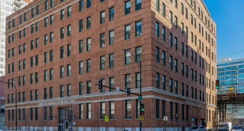 Exterior of Carriage House Lofts building, a brick facade with multiple windows on a sunny day in Chicago