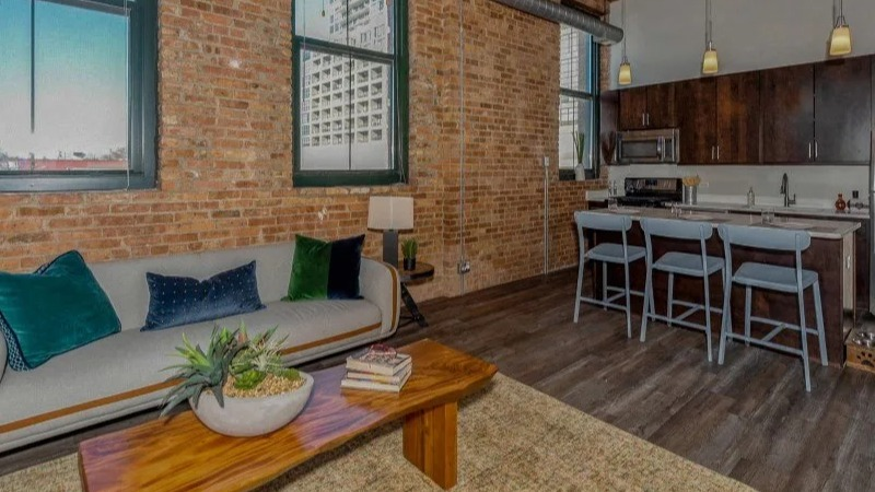 Living room with a modern sofa and a view into the kitchen bar area at Carriage House Lofts in Chicago