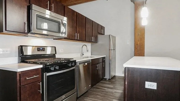 Modern kitchen with stainless steel appliances, dark wood cabinets, and an island at Carriage House Lofts in Chicago