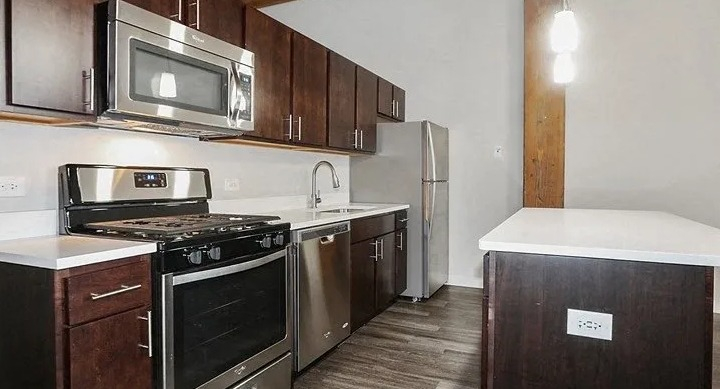 Modern kitchen with stainless steel appliances, dark wood cabinets, and an island at Carriage House Lofts in Chicago