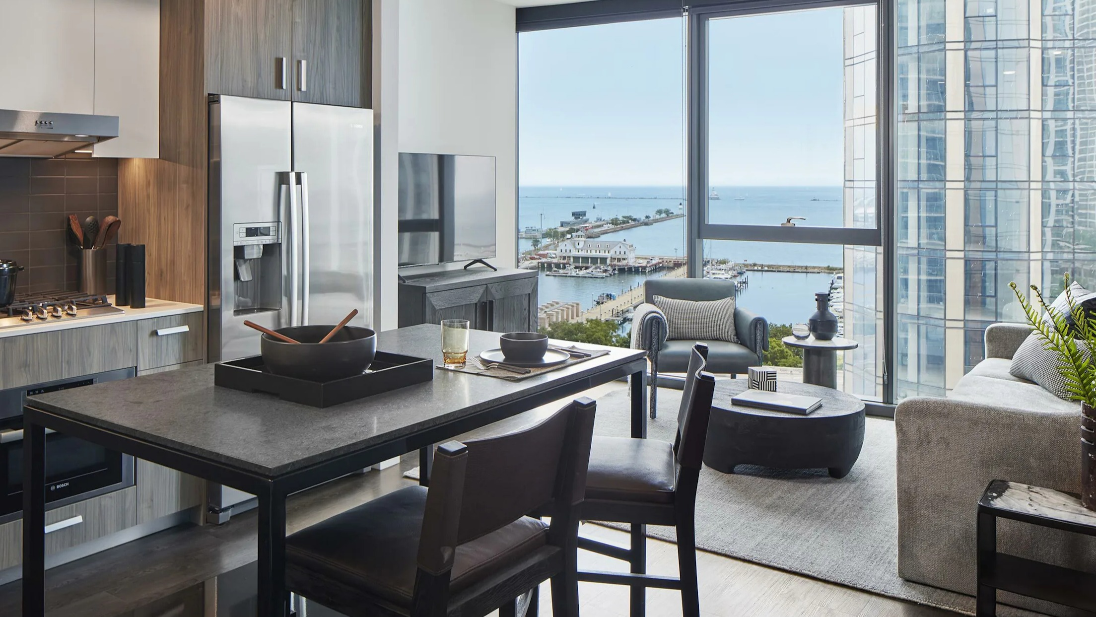 Modern apartment living and dining area with stunning lake views from large windows at Cascade Lakeshore East in Chicago