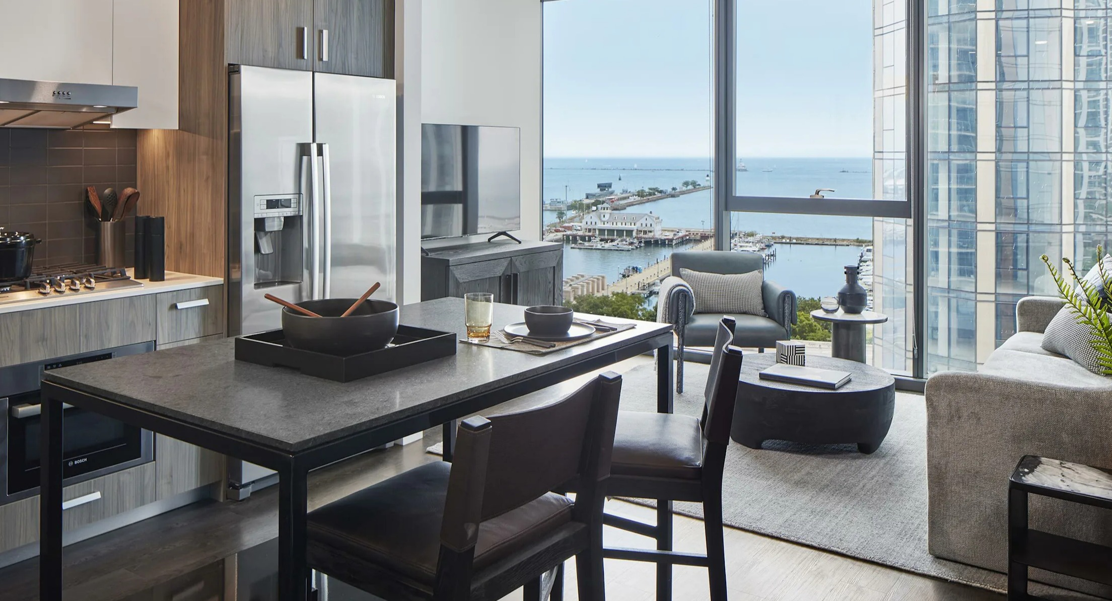 Modern apartment living and dining area with stunning lake views from large windows at Cascade Lakeshore East in Chicago